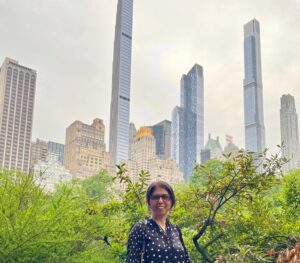 Sharmin Banu, Executive coach standing in front of greenery overlooking tall buildings