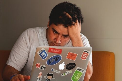 A young man frustratingly looking at a laptop screen
